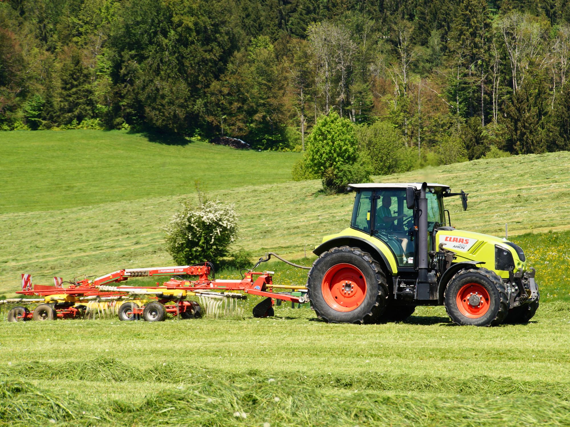 Traktor beim Heuwenden auf dem Ferienhof Eger – echtes Bauernhofleben auf grüner Wiese in der Natur