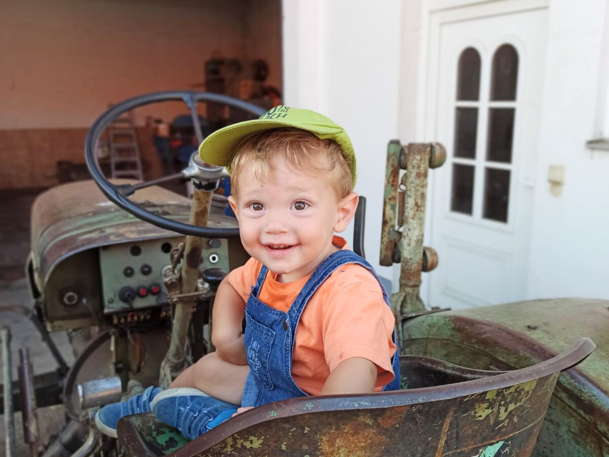 Kleiner Junge sitzt lachend auf einem alten Traktor am Ferienhof Eger – authentischer Familienurlaub auf dem Bauernhof