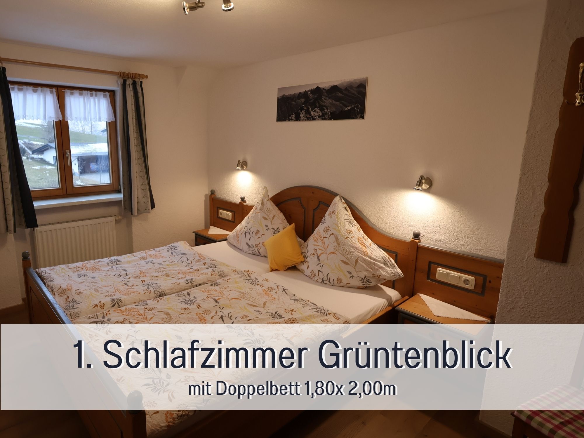 Erstes Schlafzimmer der Ferienwohnung Grüntenblick mit Doppelbett, Leselampen und Fensterblick – ideal für Eltern im Allgäu-Urlaub