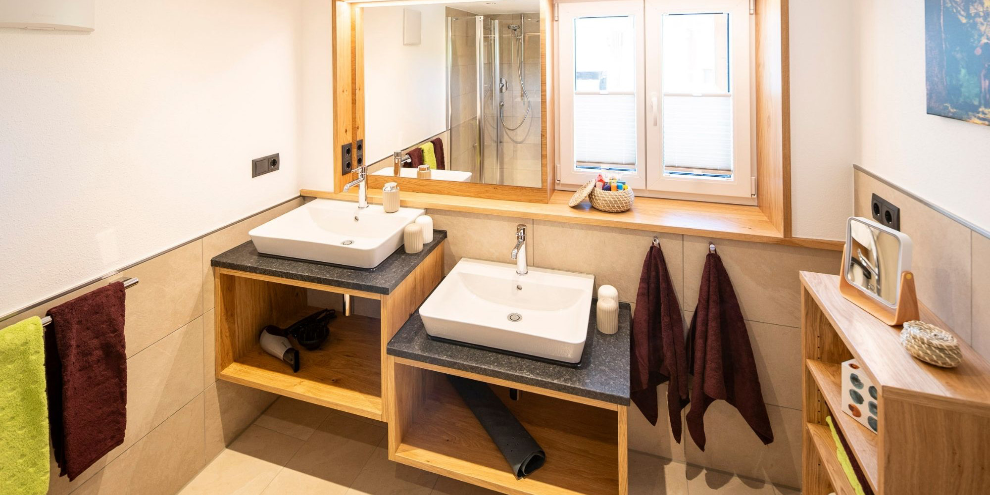 Modernes Badezimmer mit zwei Waschbecken, Dusche, Tageslichtfenster und Handtuchausstattung – Ferienwohnung Morgensonne im Allgäu