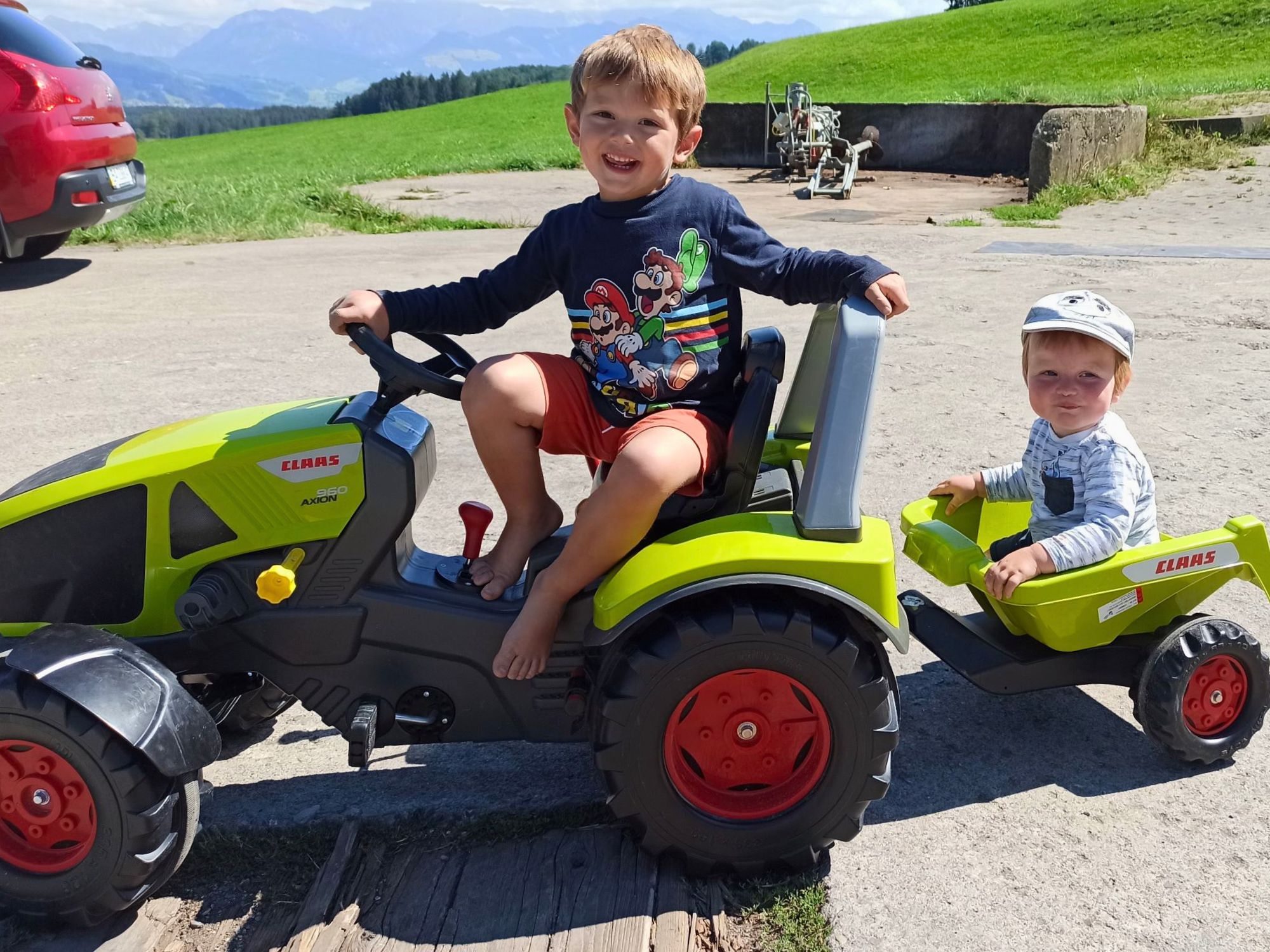 Zwei Kinder beim Spielen mit dem Trettraktor auf dem Ferienhof – Bauernhoferlebnis für Familien im Allgäu