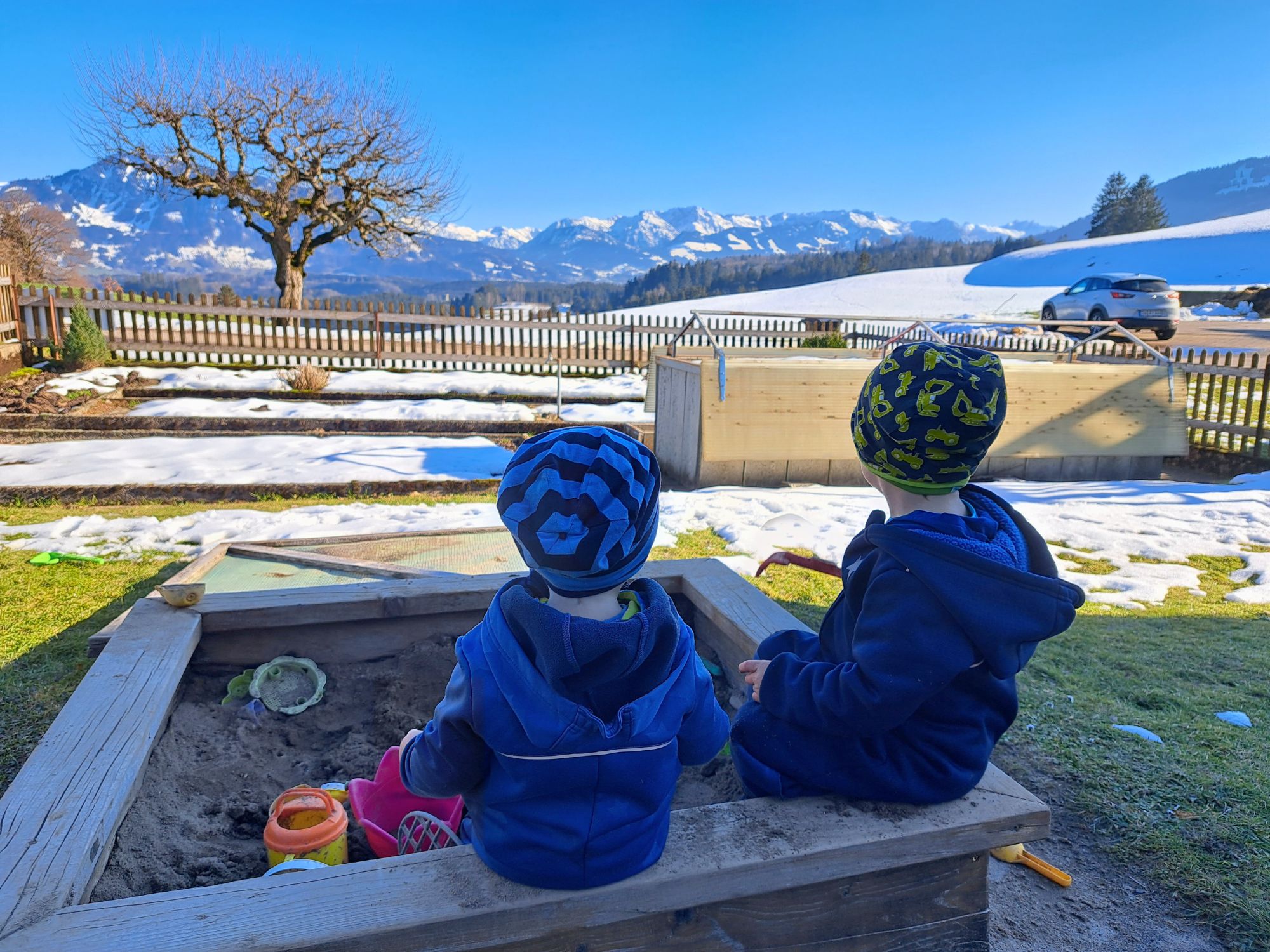 Zwei Kinder spielen im Sandkasten mit Blick auf die Allgäuer Berge – ruhiger Familienurlaub auf dem Bauernhof